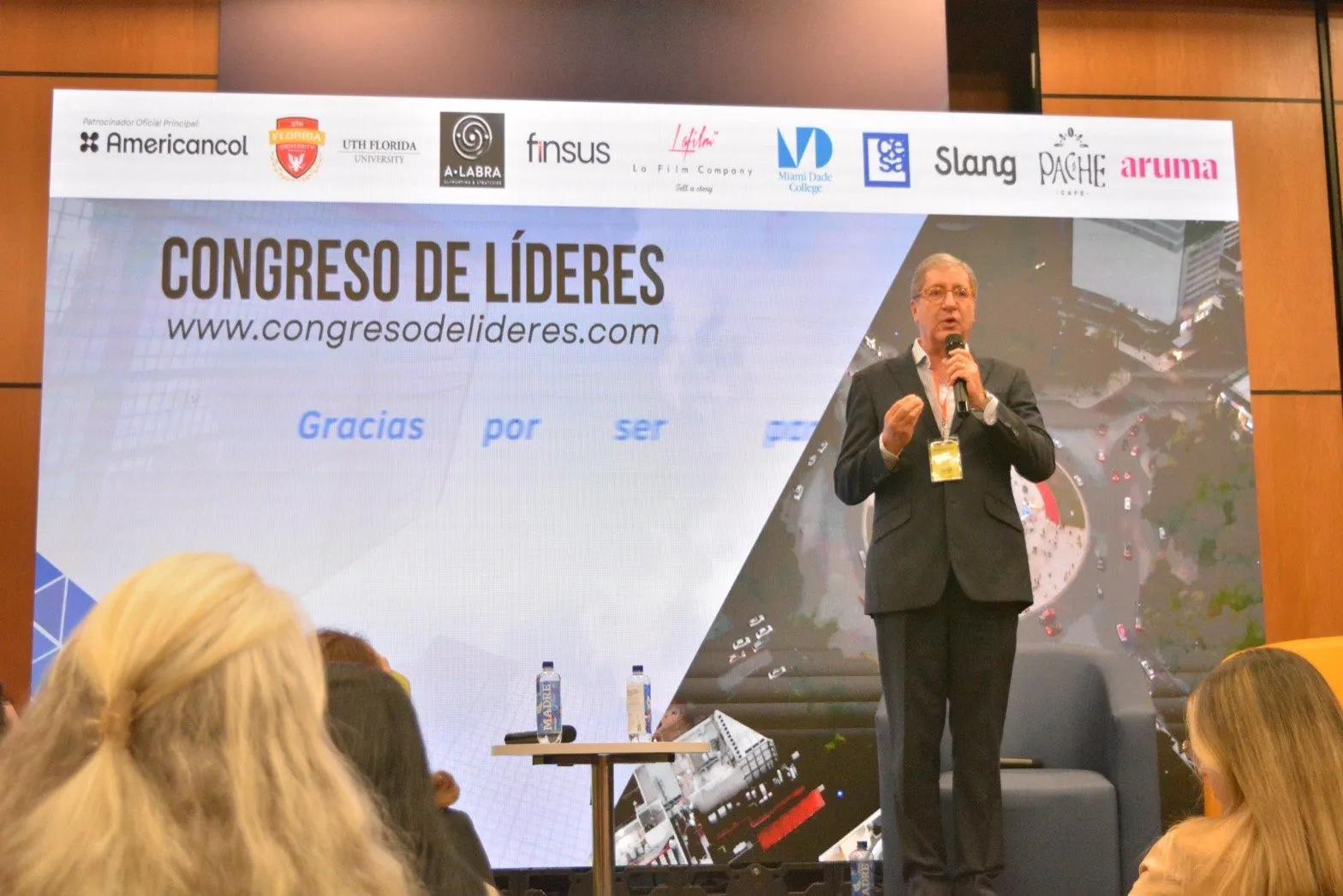 Conferencista en la tarima del Congreso de Líderes frente a la pantalla con el telón de patrocinadores