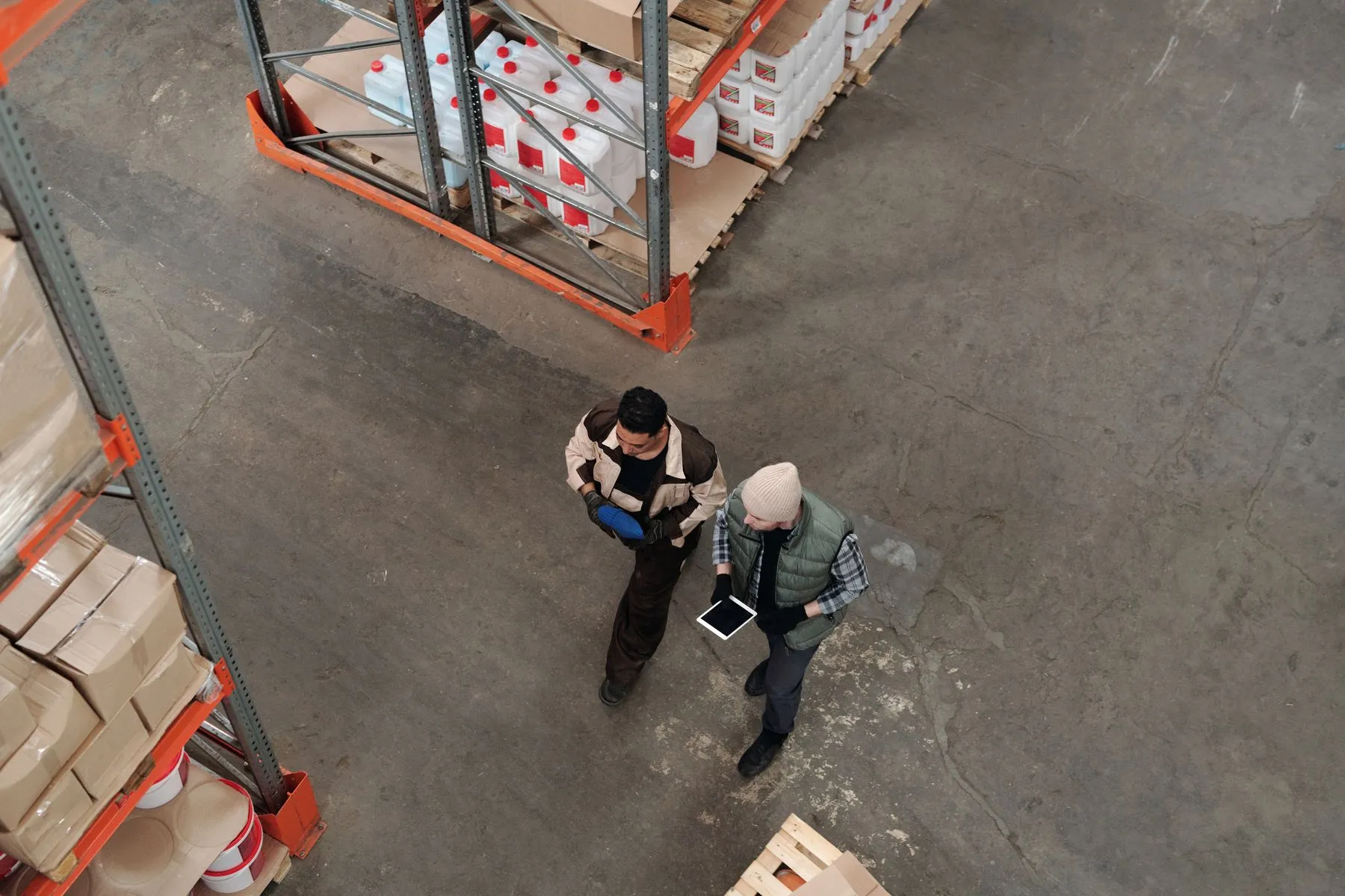 Dos operarios revisan inventario con una tableta entre estanterías de un centro de distribución