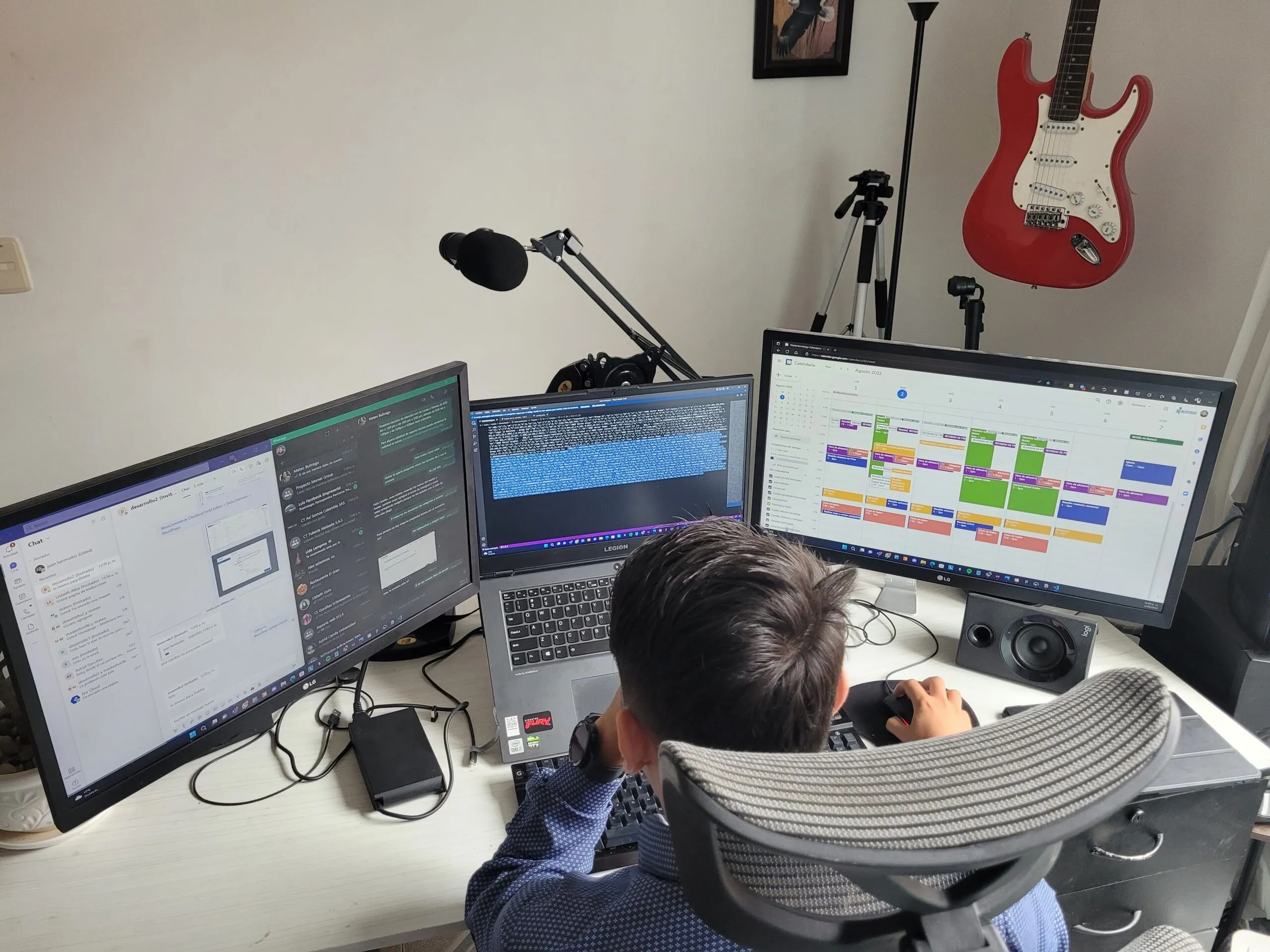 Un integrante del equipo de MTechnology trabaja frente a tres pantallas con el chat del equipo, código y el calendario de proyectos