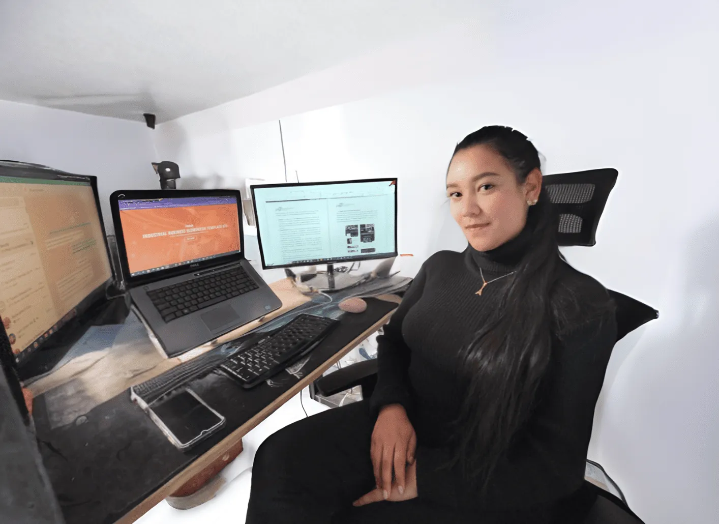 Una integrante del equipo de MTechnology en su puesto de trabajo, junto a dos monitores y un portátil