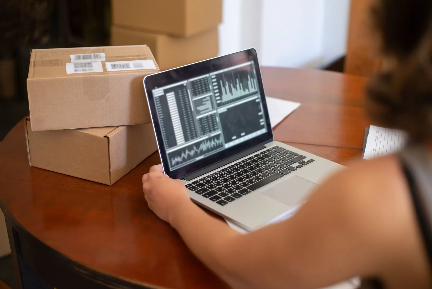 Un tablero de ventas en un portátil junto a cajas de despacho ya rotuladas