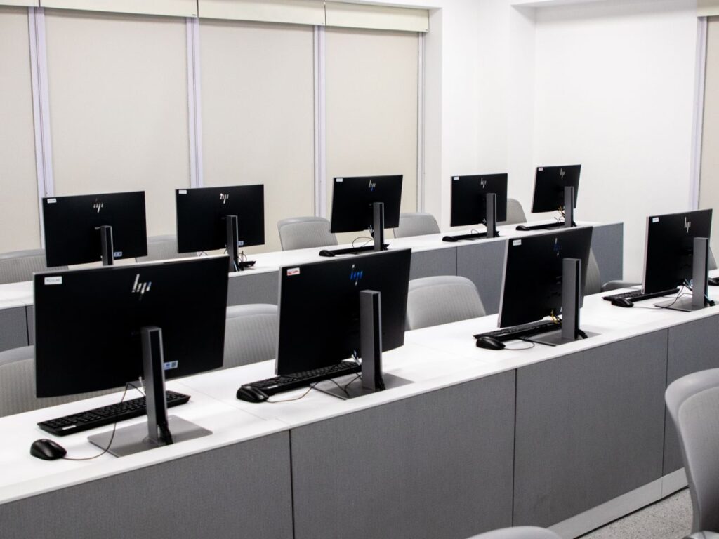 Aula de informática con filas de computadores de escritorio, entorno donde se usa una plataforma Moodle
