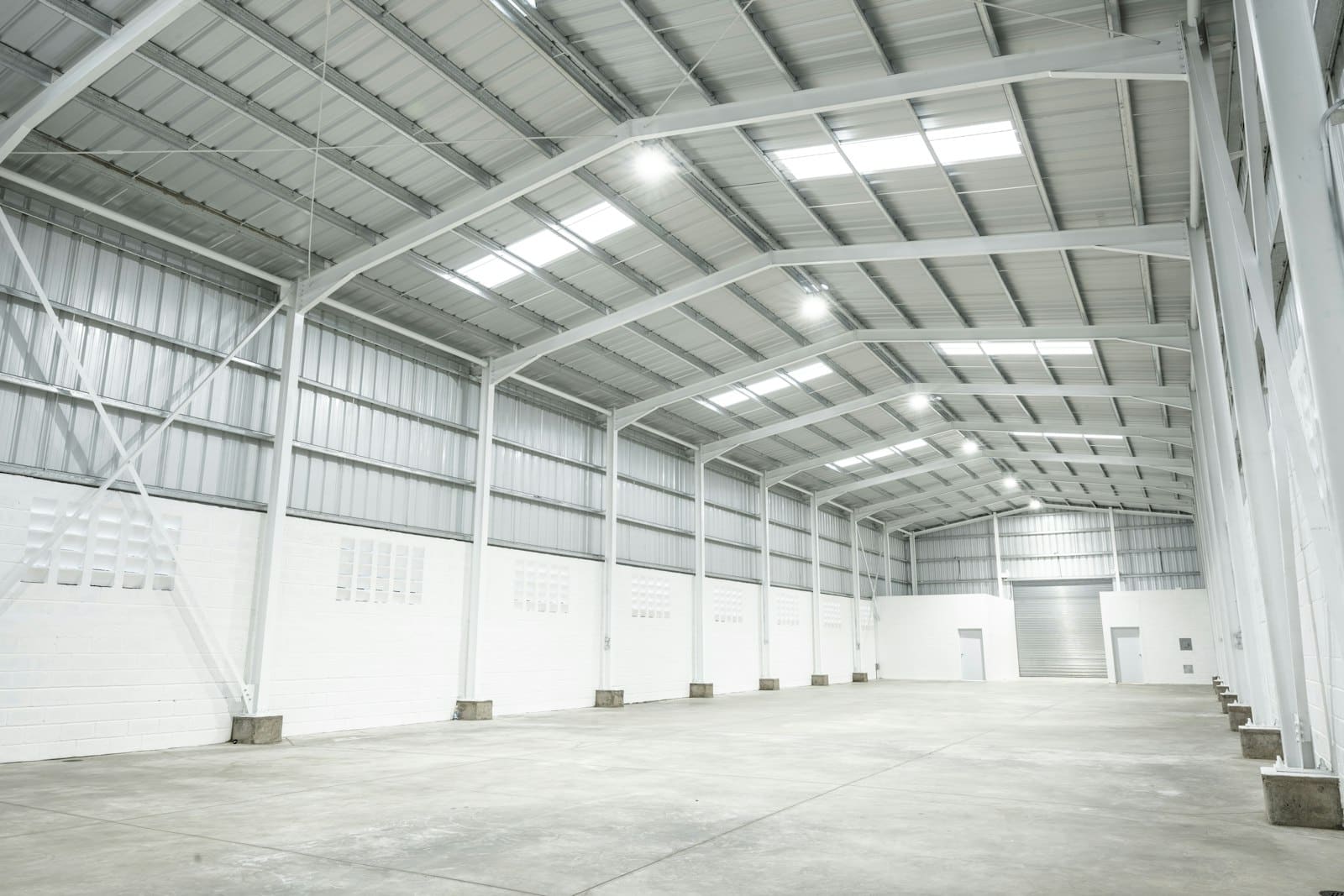 Nave industrial amplia y vacía con estructura metálica blanca, imagen de referencia de una operación logística donde se automatizan pedidos