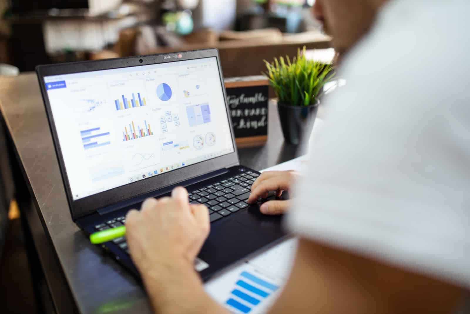 Persona revisando gráficas de análisis en una laptop, en una oficina moderna, para comparar el costo de un software por suscripción con uno a la medida
