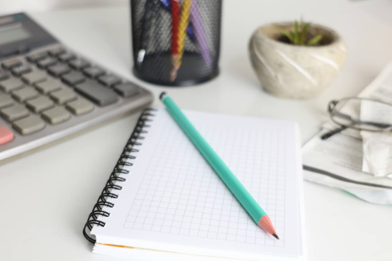 Escritorio con calculadora, cuaderno cuadriculado y lápiz, imagen de la gestión contable y de facturación