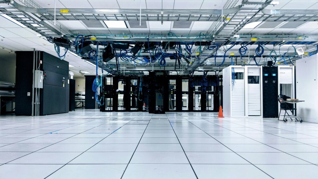 Sala de servidores con gabinetes negros y blancos bajo bandejas de cables azules, imagen de infraestructura donde se integran los sistemas de una empresa